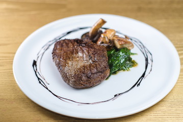 steak with mushrooms and spinach on a white plate