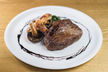 steak with mushrooms and spinach on a white plate