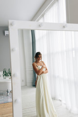 The bride's dress hangs on the mirror.