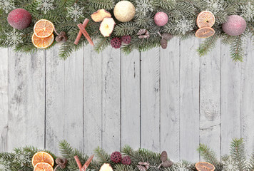 Christmas fir branches with christmas fruits, white snowflakes as a border against a wood background 