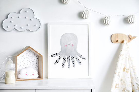 Stylish scandinavian nursery shelf with mock up photo frame, bottle with milk and toys. Modern interior with white walls and wooden accessories.