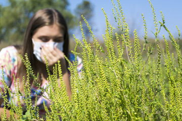 Young woman sneezes because of an allergy to ragweed.