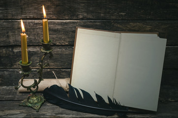 Open book with blank empty pages in the light of burning candle. Writer or author concept.