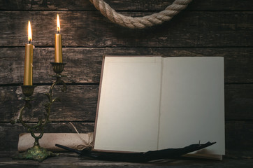 Open book with blank empty pages in the light of burning candle. Writer or author concept.