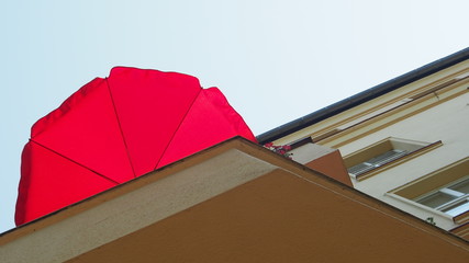 Fototapeta premium Sommer auf dem Balkon: Roter Sonnenschirm