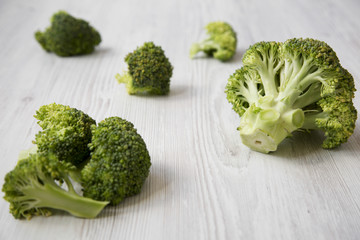 Raw broccoli on white wooden table, side view.
