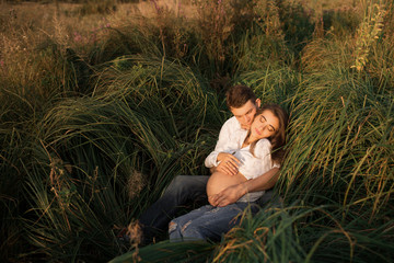 A pregnant woman with her husband. Young couple expecting a baby cuddling at ninth month of...