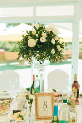 Arch on festive table newlyweds covered with a tablecloth and decorated with composition of flowers and greenery, candles in the wedding banquet hall. Wedding party in tent.
