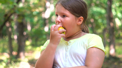 Little girl portrait eating apple outdoor apple in a summer day