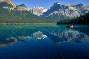 family canoeing across emerald lake