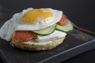 bagels with egg and cucumber on black background.