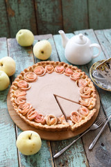 Apple rose pie with cream filling served with organic apples and tea on coarse wood blue background