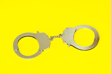 Metal handcuffs isolated on yellow background