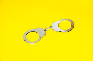 Metal handcuffs isolated on yellow background
