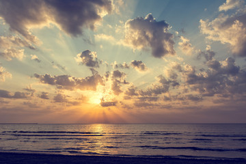Wonderful sunrise over the sea with golden sun, clouds and light rays