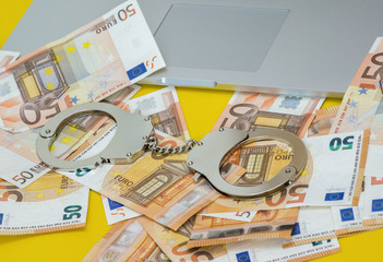 Handcuffs with money on the laptop keyboard.