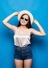 Portrait of stylish cute smiling asian girl wears straw hat and trendy glasses posing on blue background