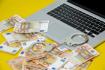Handcuffs with money on the laptop keyboard.