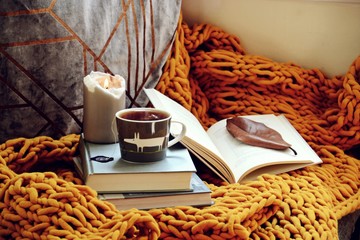 Cozy home with cup of tea with blanket and book. Hygge home interior 