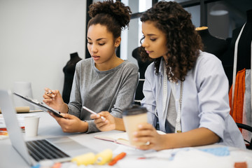African American women working together in creative office, drawing, sketching, drinking coffee....