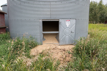 granary bin with an open door and spilt wheat