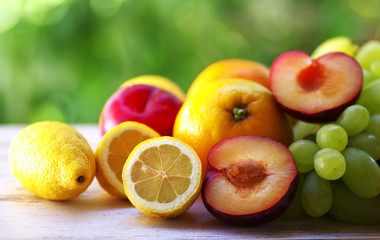 citric fruits, plums and grapes on wooden table