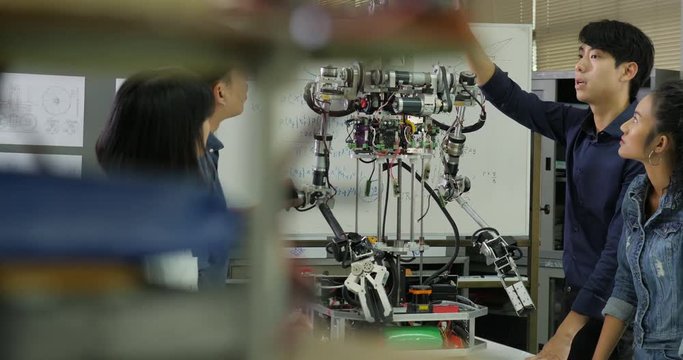 Young electronics engineer team collaborating on construction of robot in the workshop. Team engineer start up for robot project together. People with technology or innovation concept.