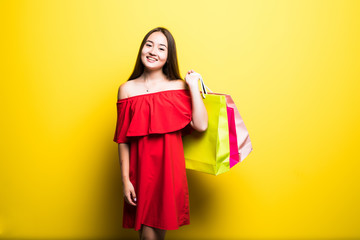 Beautiful young asian woman with shopping bags on yellow background. Shopaholic shopping Fashion.