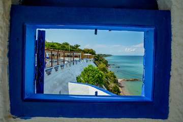 View from a Window at a Tavern at a Traditional Greek White Windmill on the Sea Shore on a Bright Sunny Day