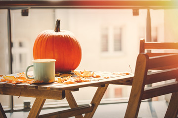 cup of coffee and pumpkin on table with leaves at balcony. Home interior