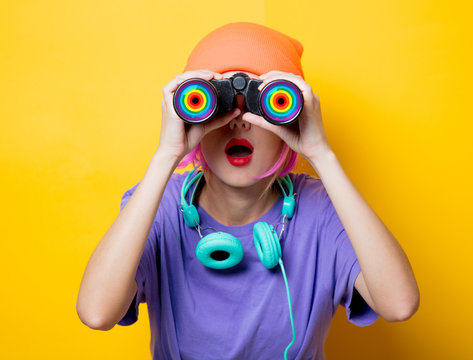 Young style girl in purple clothes with LGBT binoculars on yellow background.  Clothes in 1980s style