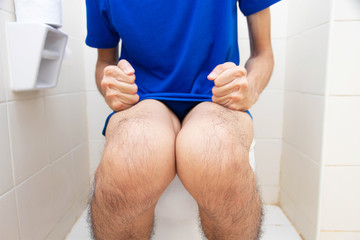 Young man suffering from constipation sitting on toilet