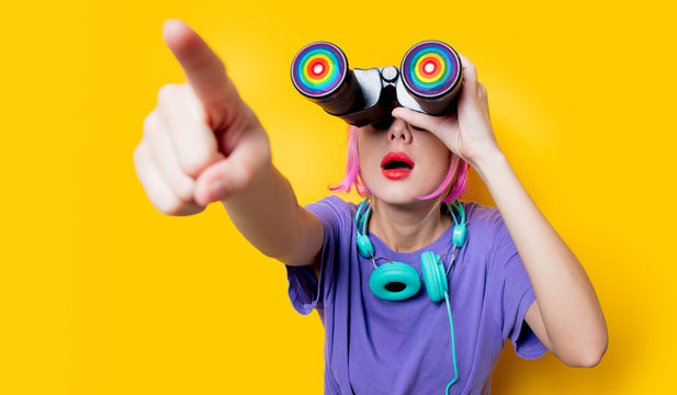 Young style girl in purple clothes with LGBT binoculars on yellow background.  Clothes in 1980s style