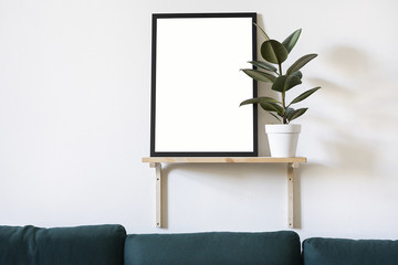 Poster in black frame in white stylish modern interior on a wall above green sofa. Design template mockup.