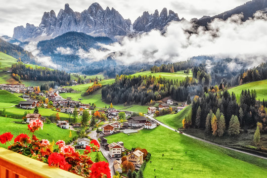 Italy, Dolomite mountains. Fascinating Alpine Village - Santa Maddalena, amazing view from balcony of hotel on flowers, green valley, Alps Odle in distance. Landscape photography, travel background.