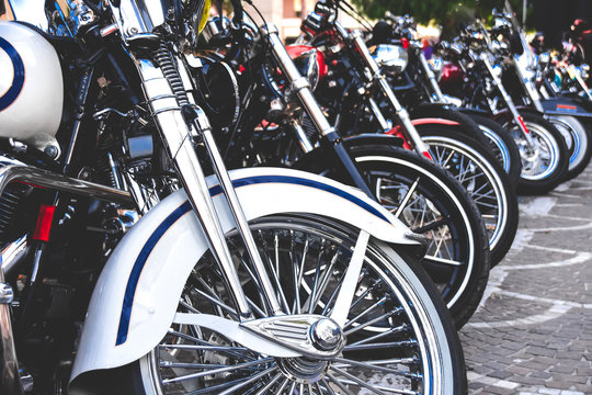 Hilera de motocicletas estilo chopper aparcadas. Fotografía desde un ángulo bajo y en primer plano de brillosas y cromadas ruedas de motos. 