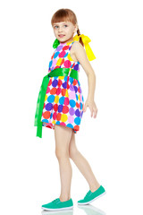 A little girl in a dress with a pattern from multi-colored circl