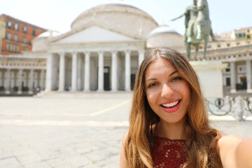 Smiling woman taking selfie photo in Naples with Piazza del Plebiscito square on the background, Naples, Italy
