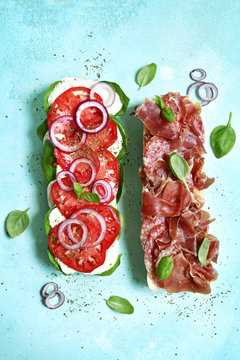 Italian sandwith with prosciutto crudo, mozzarella cheese, salame and basil.Top view with copy space.