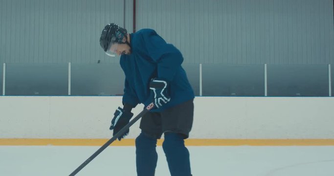 Caucasian male ice hockey player fails during skating practice at the training arena. 4K UHD 60 FPS SLOW MOTION