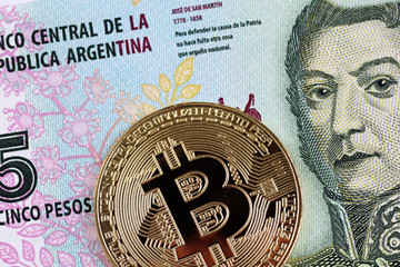 A macro image of a golden bitcoin with a five peso Argentinian bill in macro
