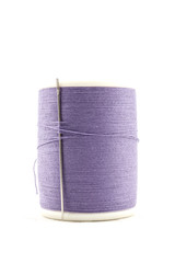 Spool of purple thread and needle on white background