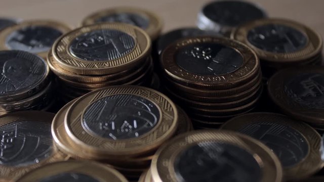 Stacks of Brazilian coins scattered across the table