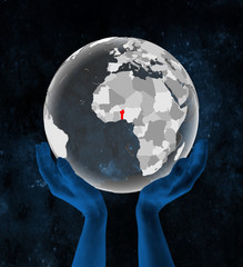 Benin on translucent globe in hands