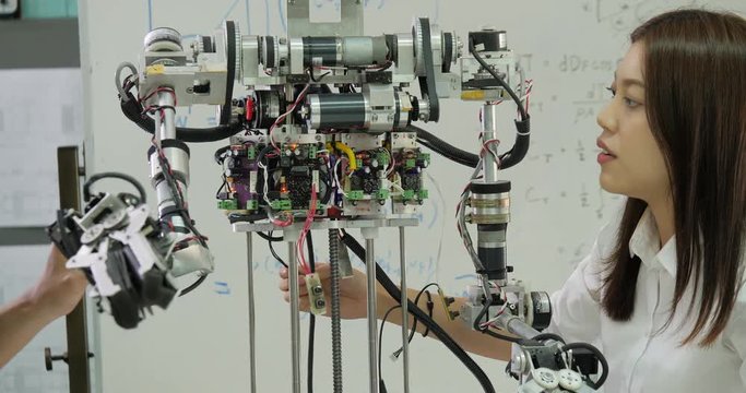 Young electronics engineer team collaborating on construction of robot in the workshop. Team engineer start up for robot project together. People with technology or innovation concept.