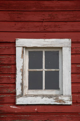 Square window with a white frame on an old red barn