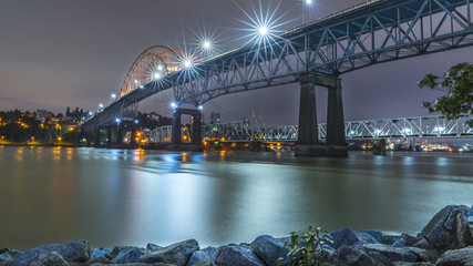 Fototapeta premium Patullo Bridge, Surrey, British Columbia, Canada. Long exposure of the bridge over the water. Sky Train Bridge.