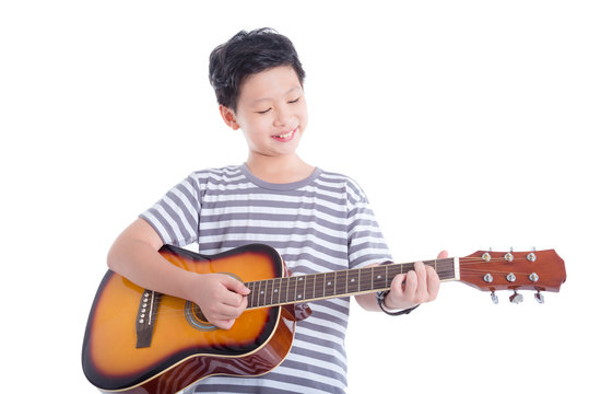 Young asian boy playing guitar and smiles over white background