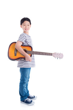 Young asian boy holding guitar and smiles over white background