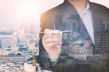 business man using airplane model with blurred city scape, concept of abstract image communication network, cyber security, internet of things, financial and future life.